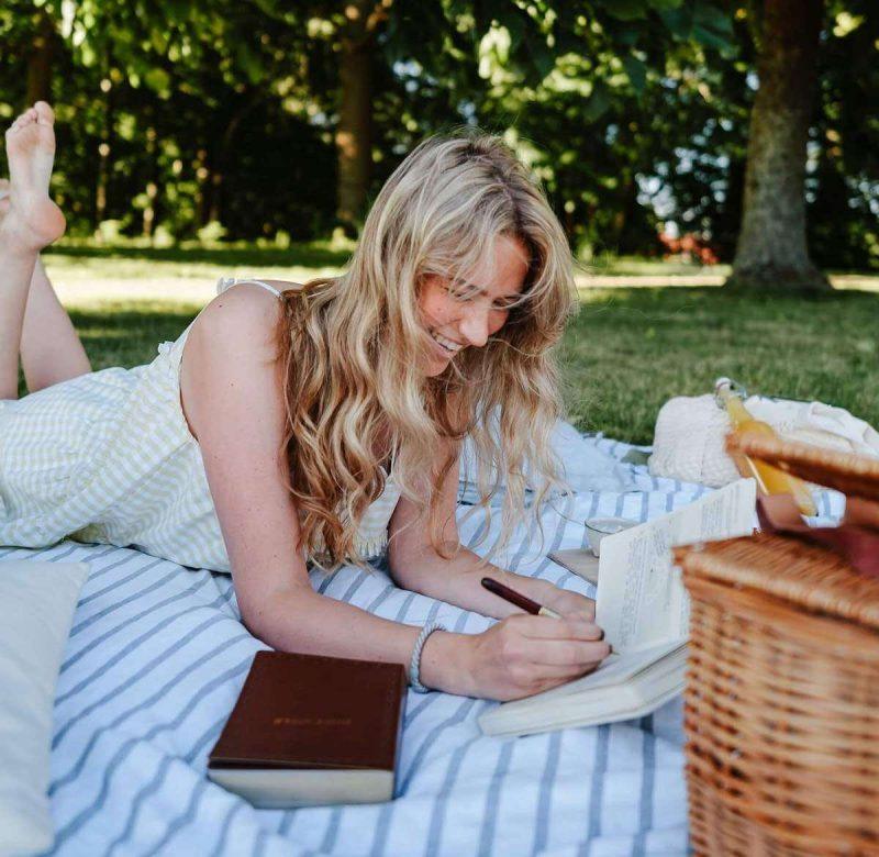 gen z lady bible journaling in park with a pic nic
